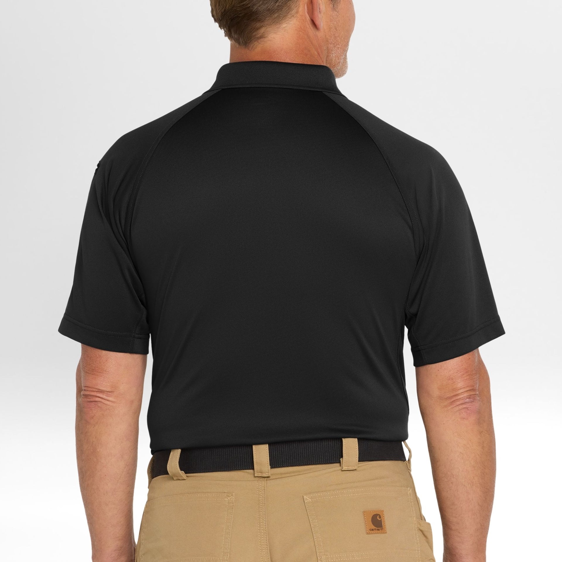 Man wearing a black Snag-Proof Tactical Polo shirt and beige pants on a white background