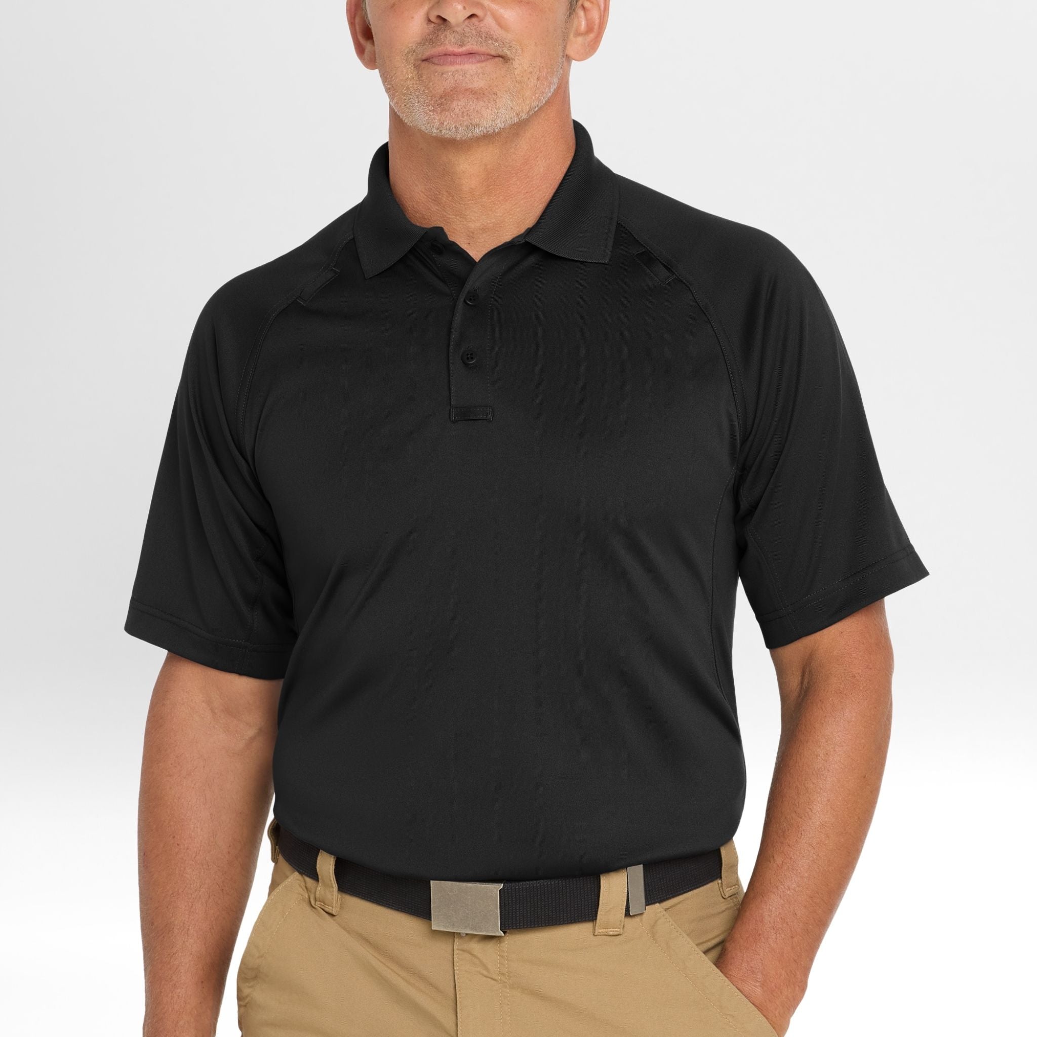 Man wearing a black Snag-Proof Tactical Polo shirt and beige pants on a white background