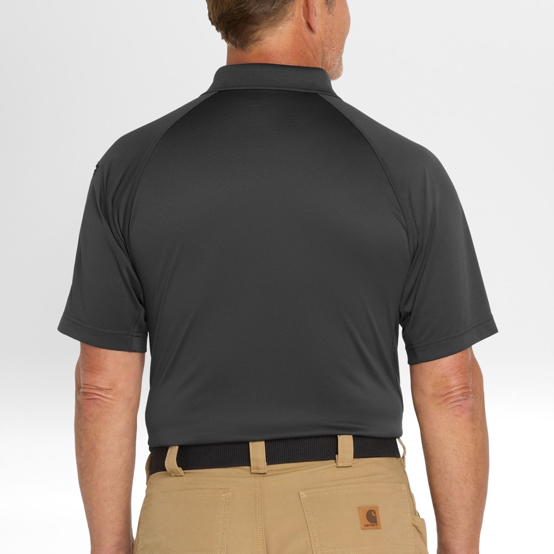 Man wearing a dark gray Snag-Proof Tactical Polo shirt and beige pants on a light gray background