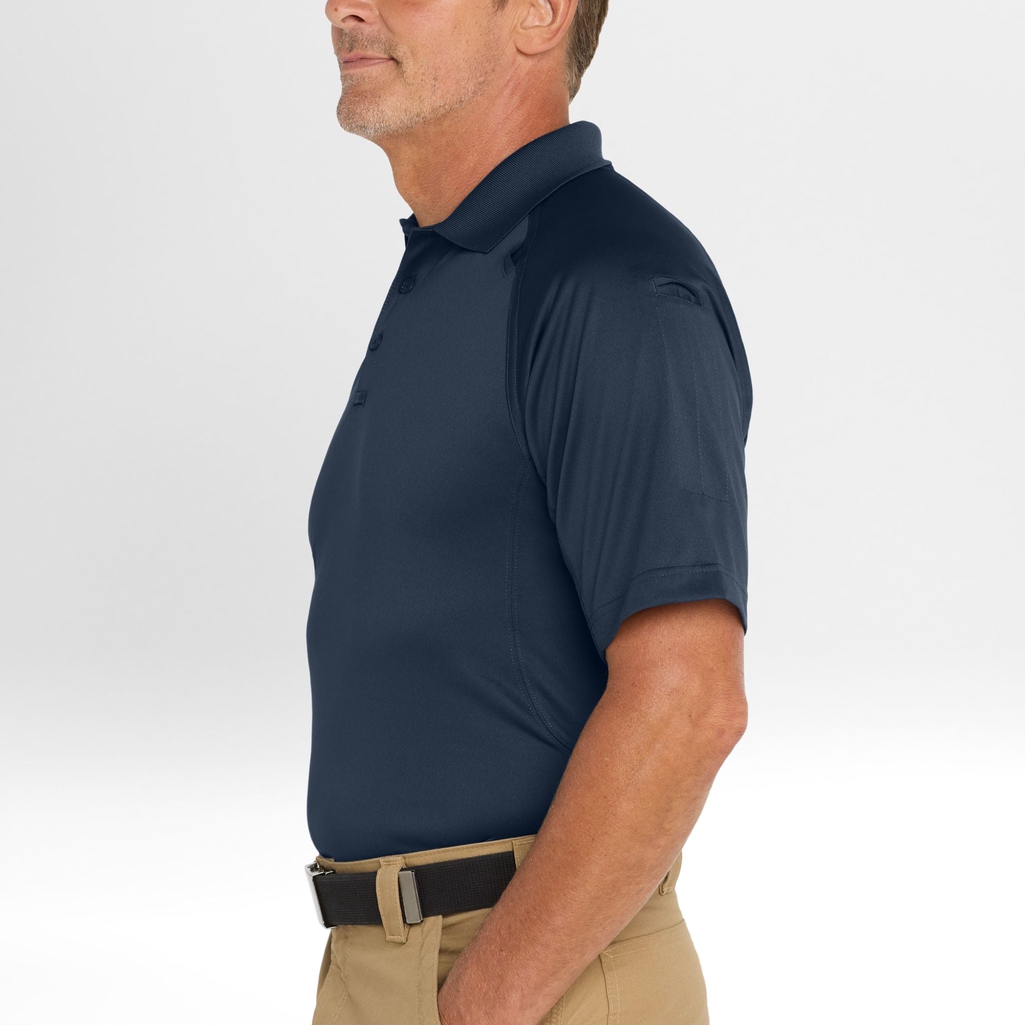 Man wearing a navy Snag-Proof Tactical Polo shirt and beige pants on a white background