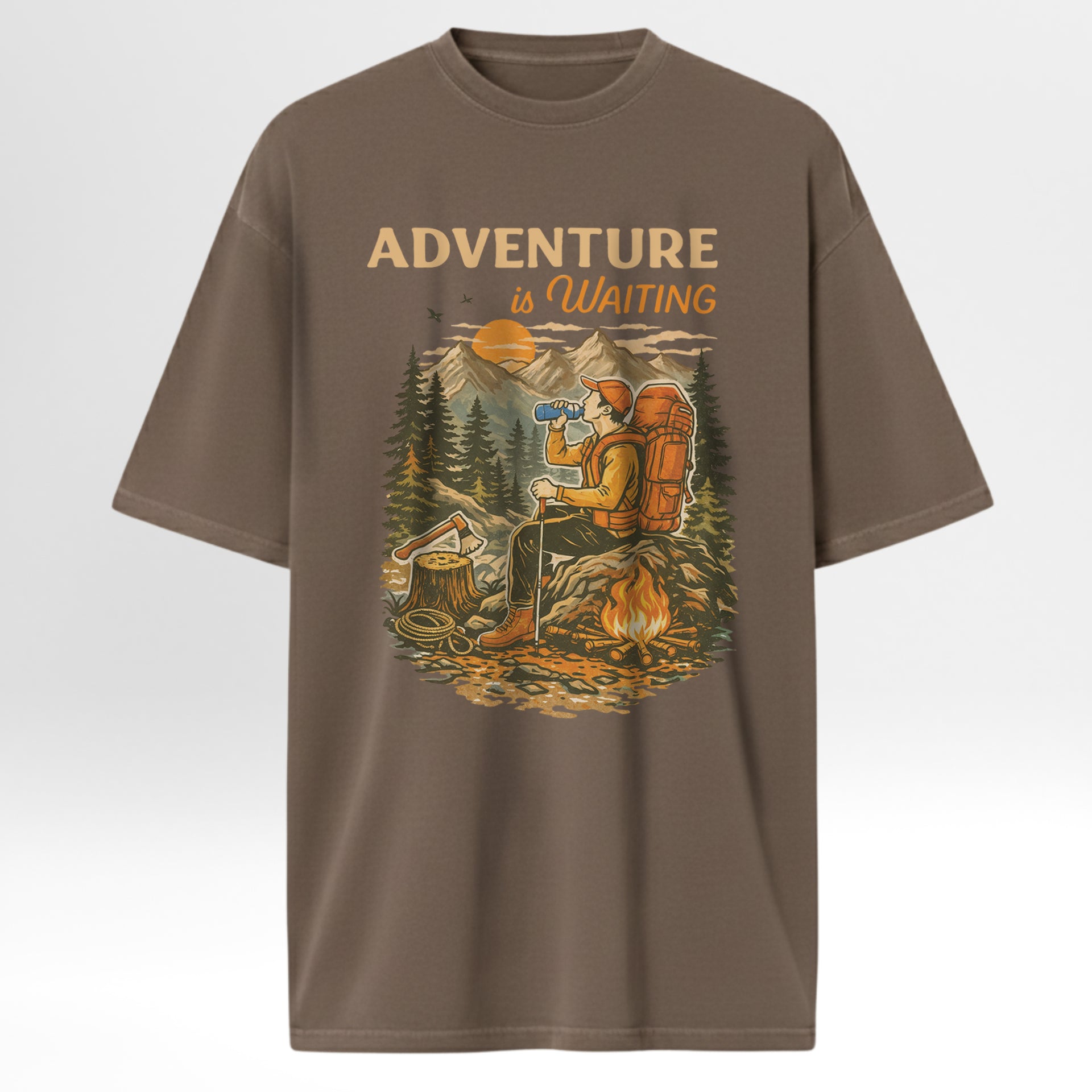Brown t-shirt with a graphic of a person by a campfire and 'Adventure is Waiting' text on a white background