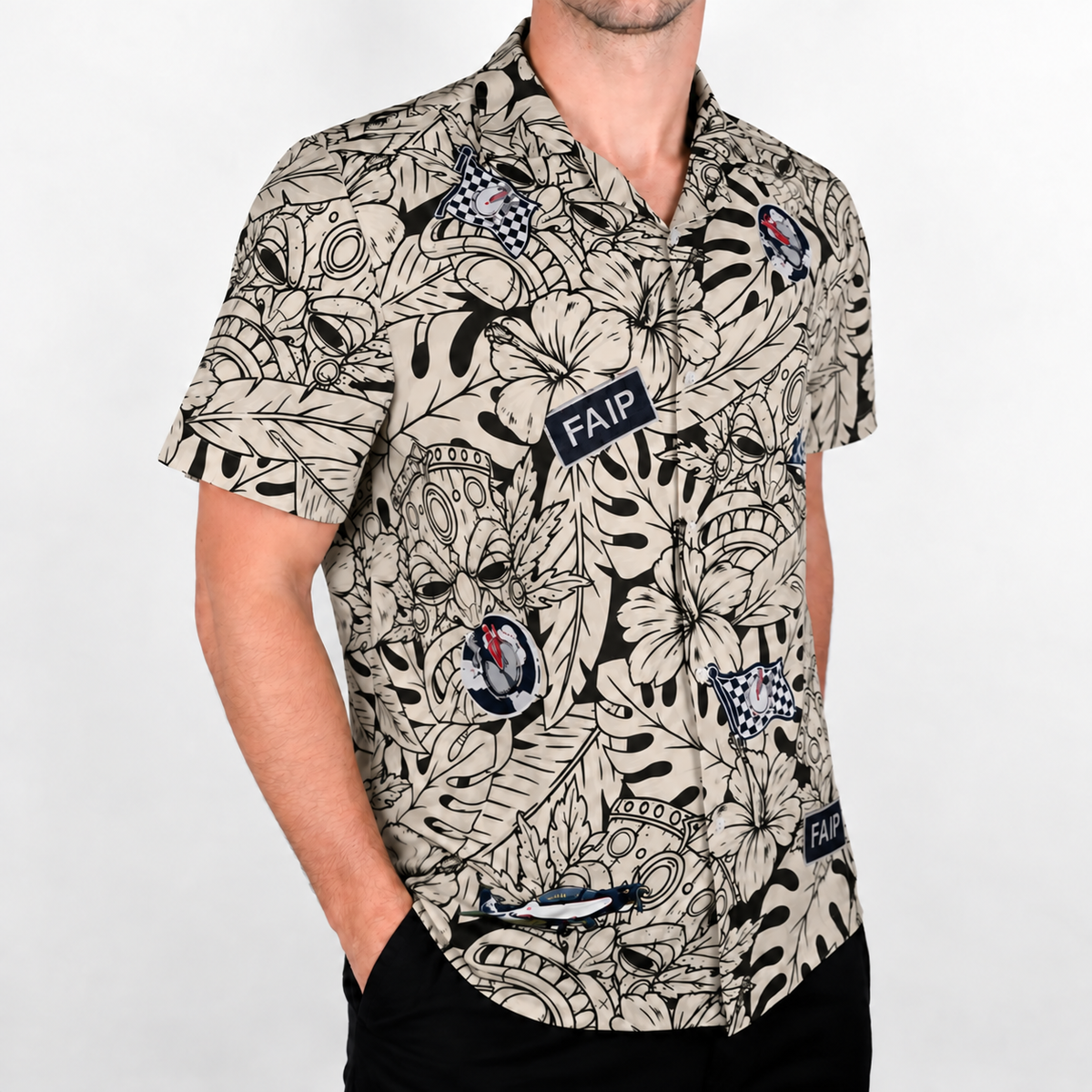 A man wearing a short-sleeve Hawaiian shirt with a beige and black tropical floral and monstera leaf print, featuring custom logos.