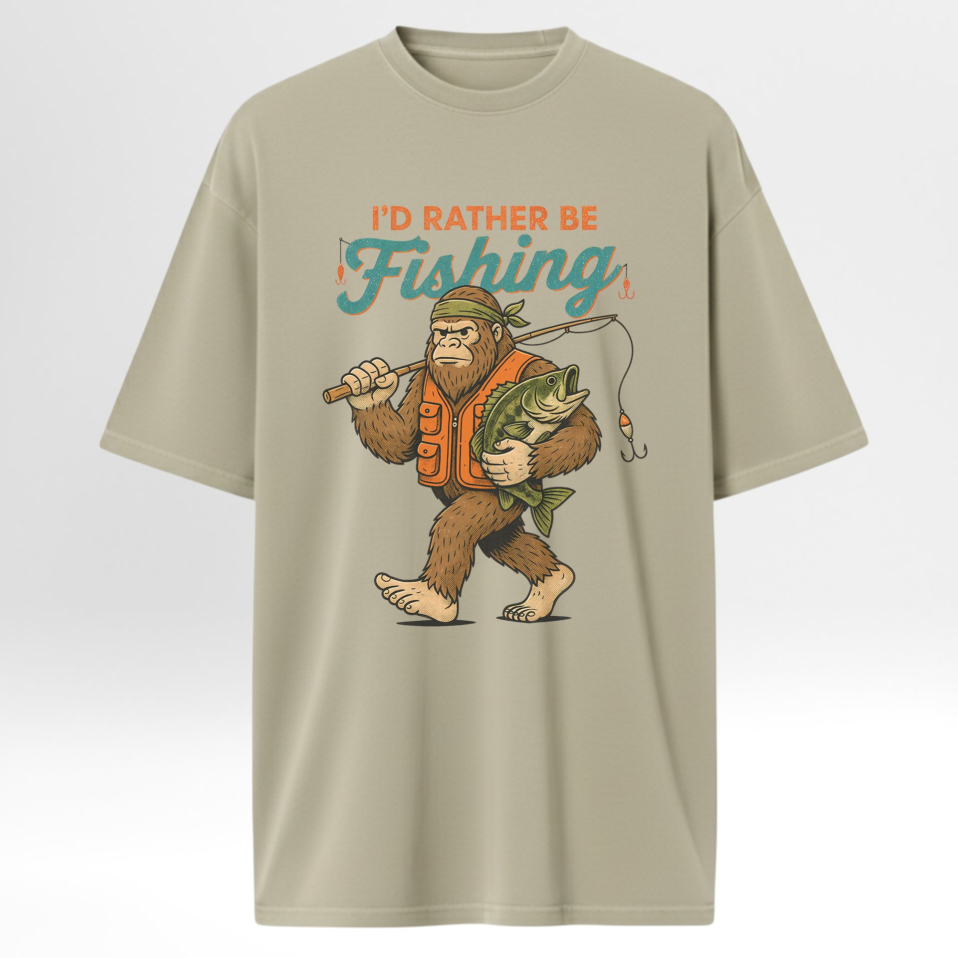 Beige fishing t-shirt with a graphic of a bigfoot holding a fish and text 'I'd Rather Be Fishing'.