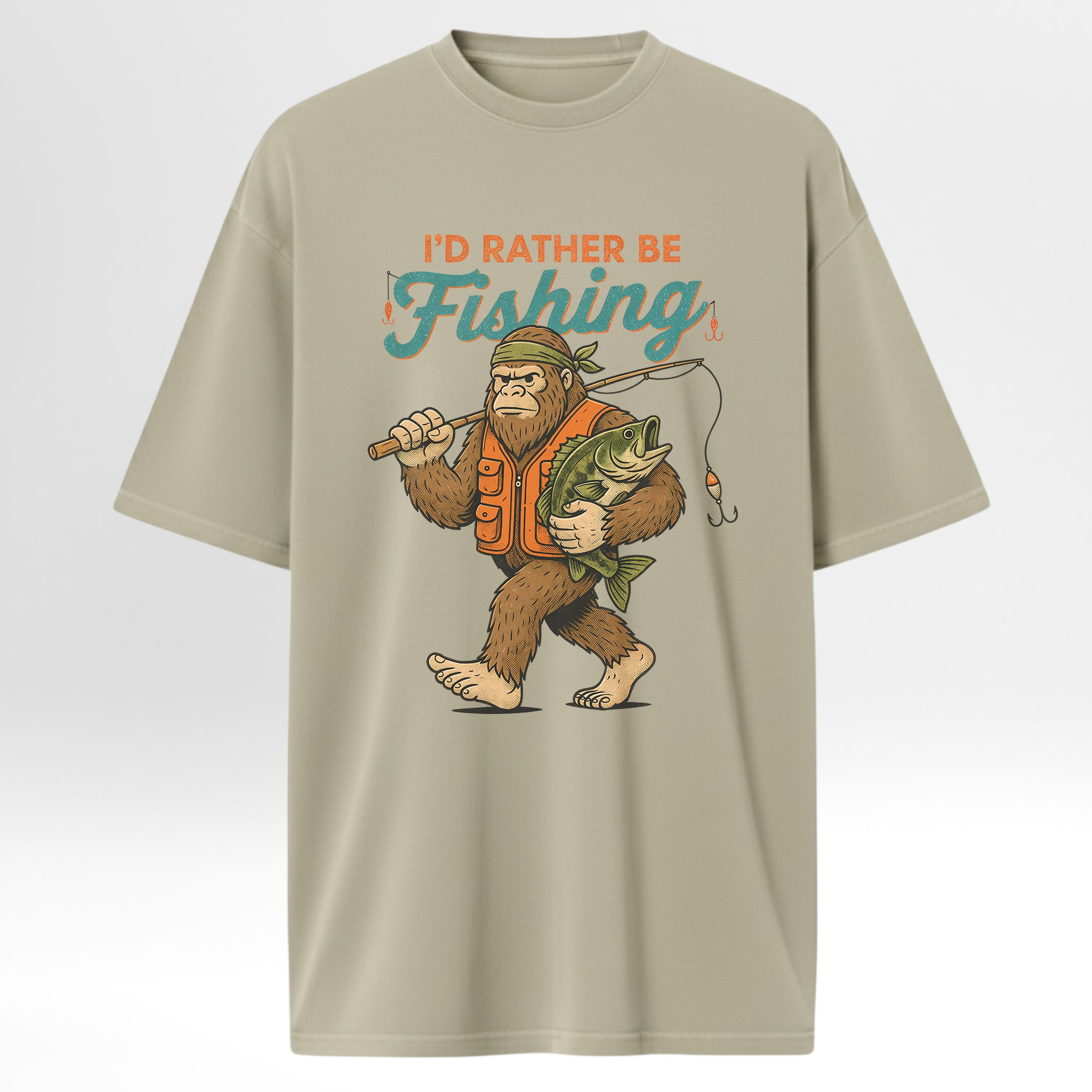 Beige fishing t-shirt with a graphic of a bigfoot holding a fish and text 'I'd Rather Be Fishing'.