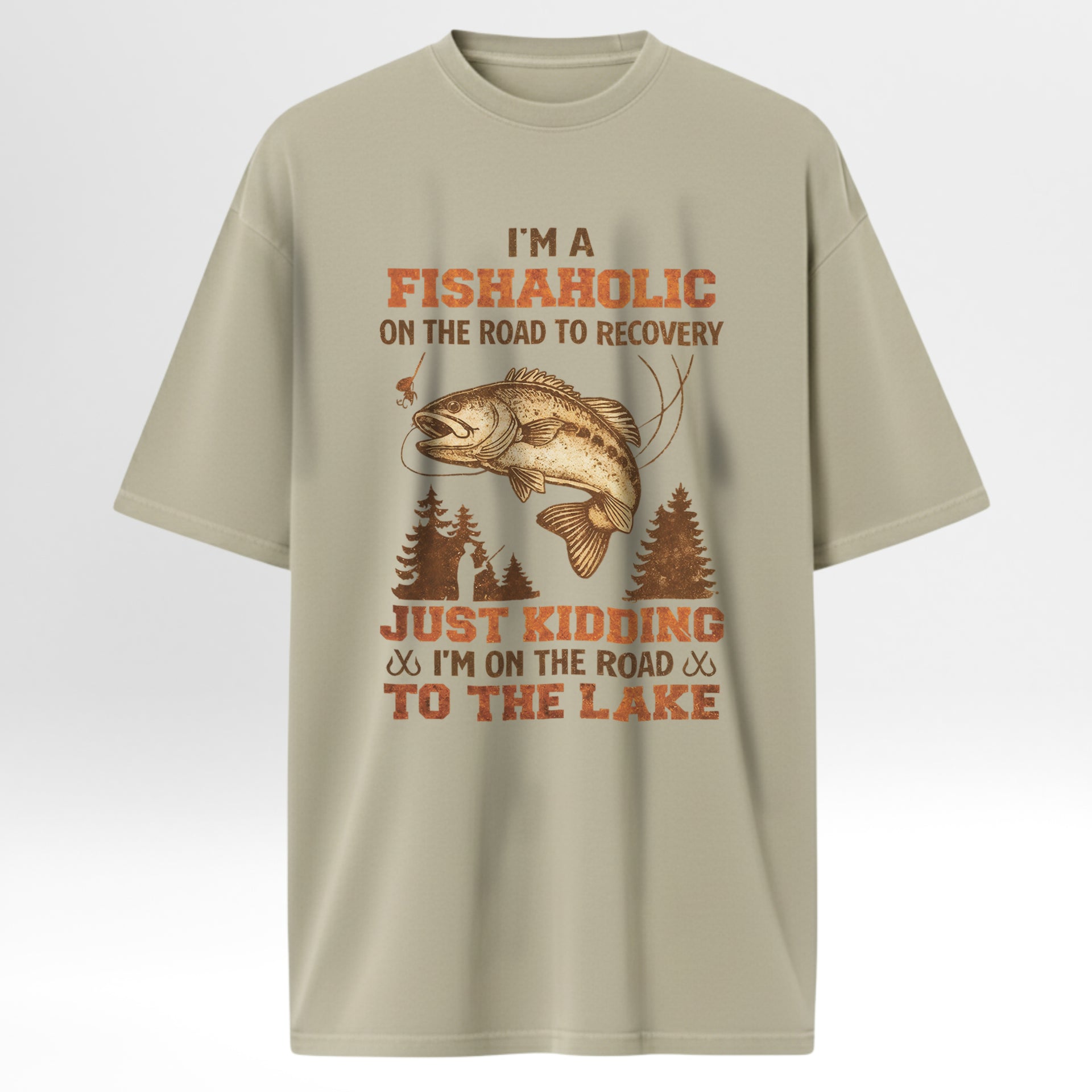 Beige fishing t-shirt with fishing graphic and humorous text 'I'm A Fishaholic On The Road To Recovery Just Kidding I'm On The Road To The Lake'