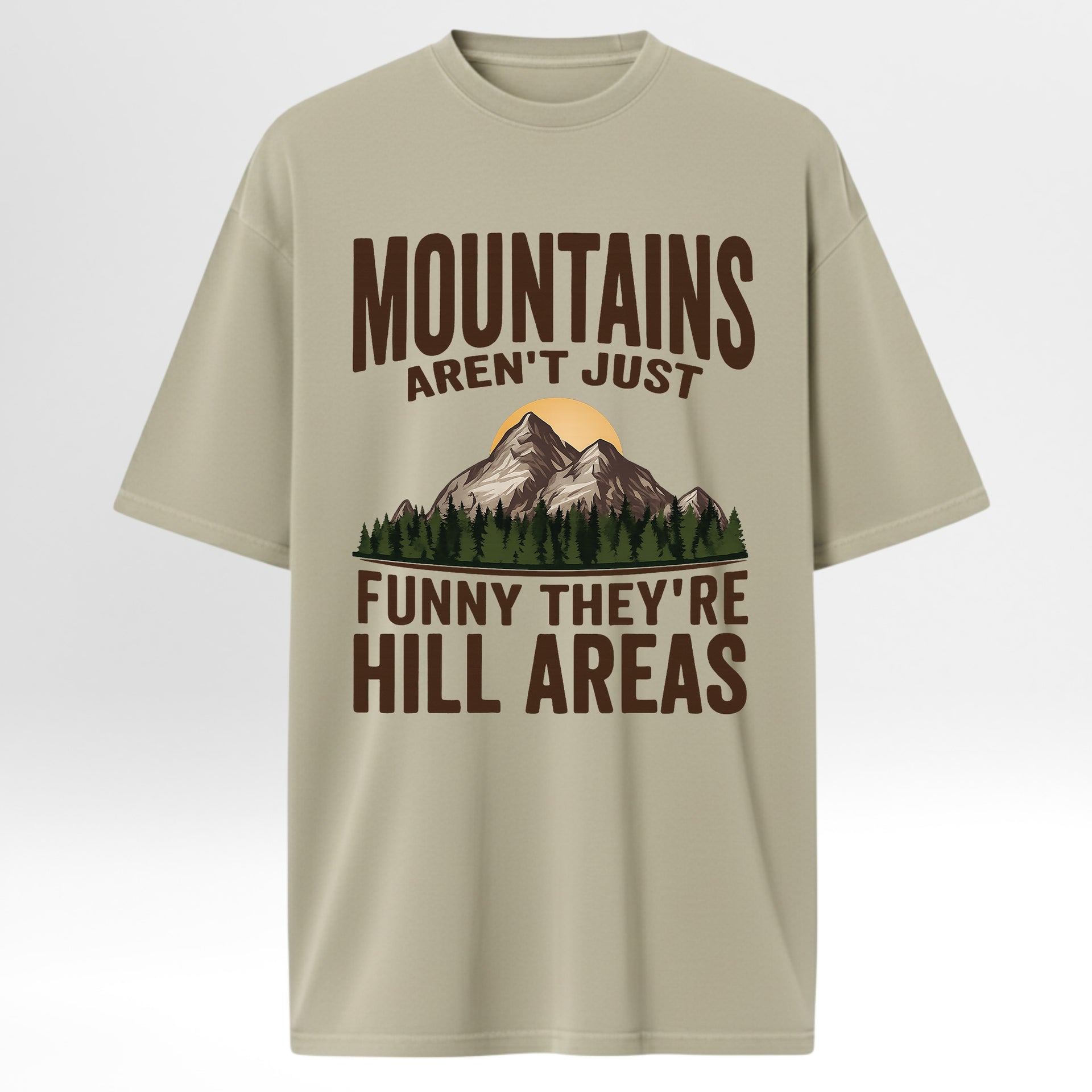 Beige t-shirt with mountain graphic and humorous text 'Mountains Aren't Just Funny They 're Hill Areas'