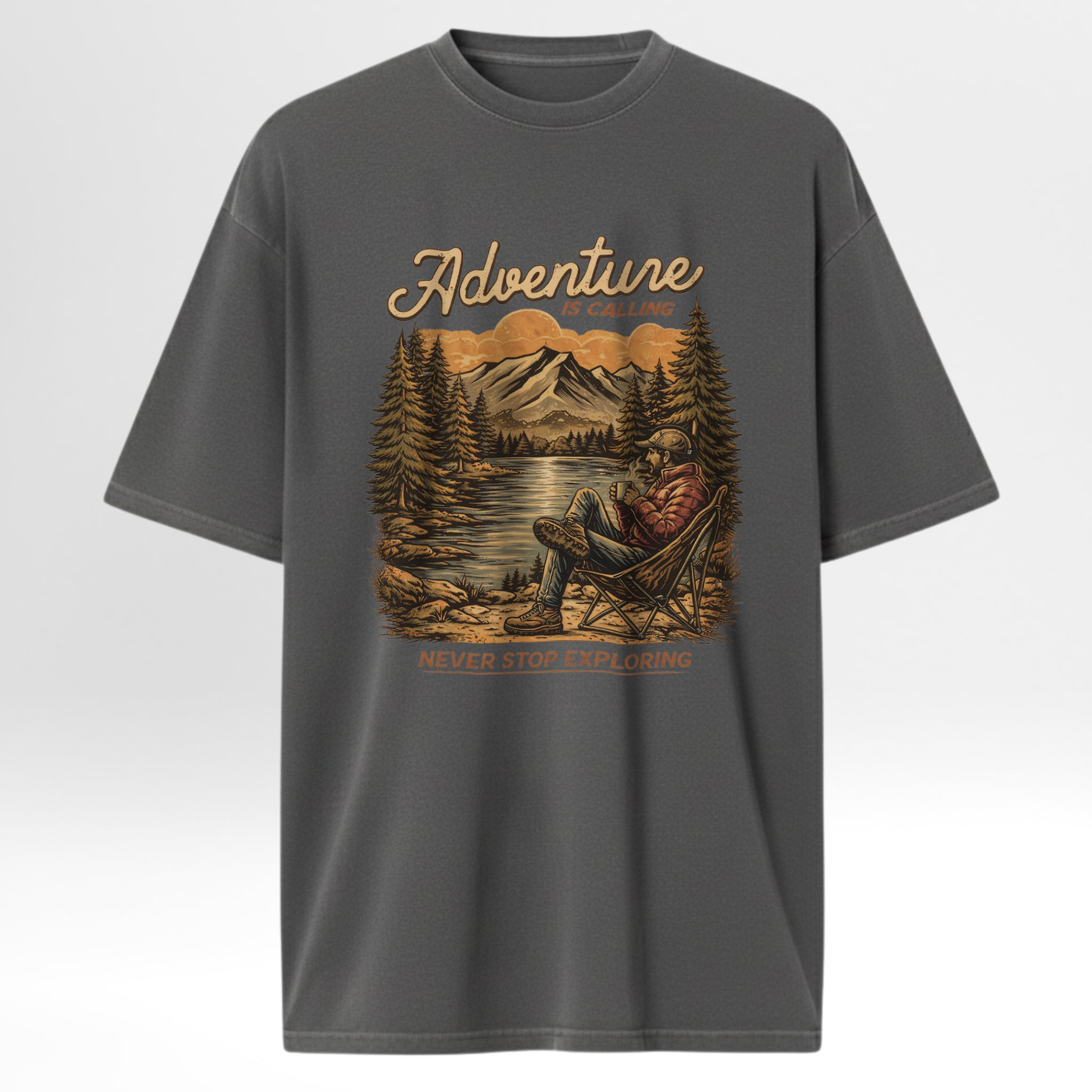 Gray t-shirt with a graphic of a person in a chair by a lake with mountains and trees, and the text 'Adventure is out there. Never stop exploring.