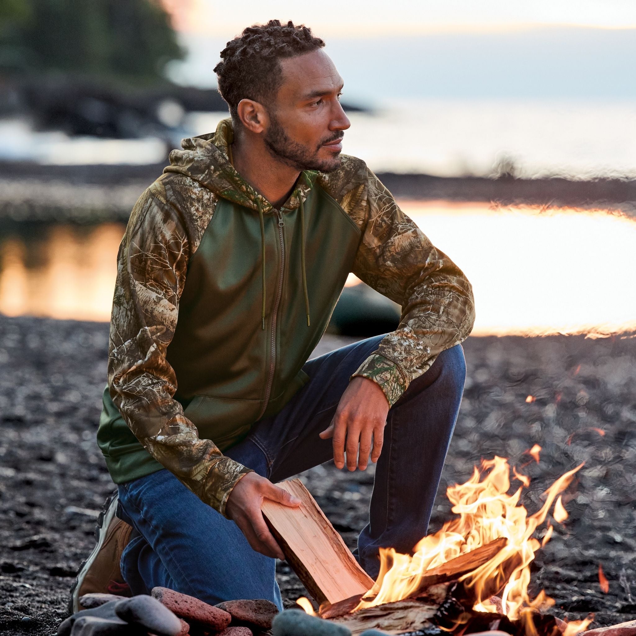 Man sitting by a campfire by a body of water