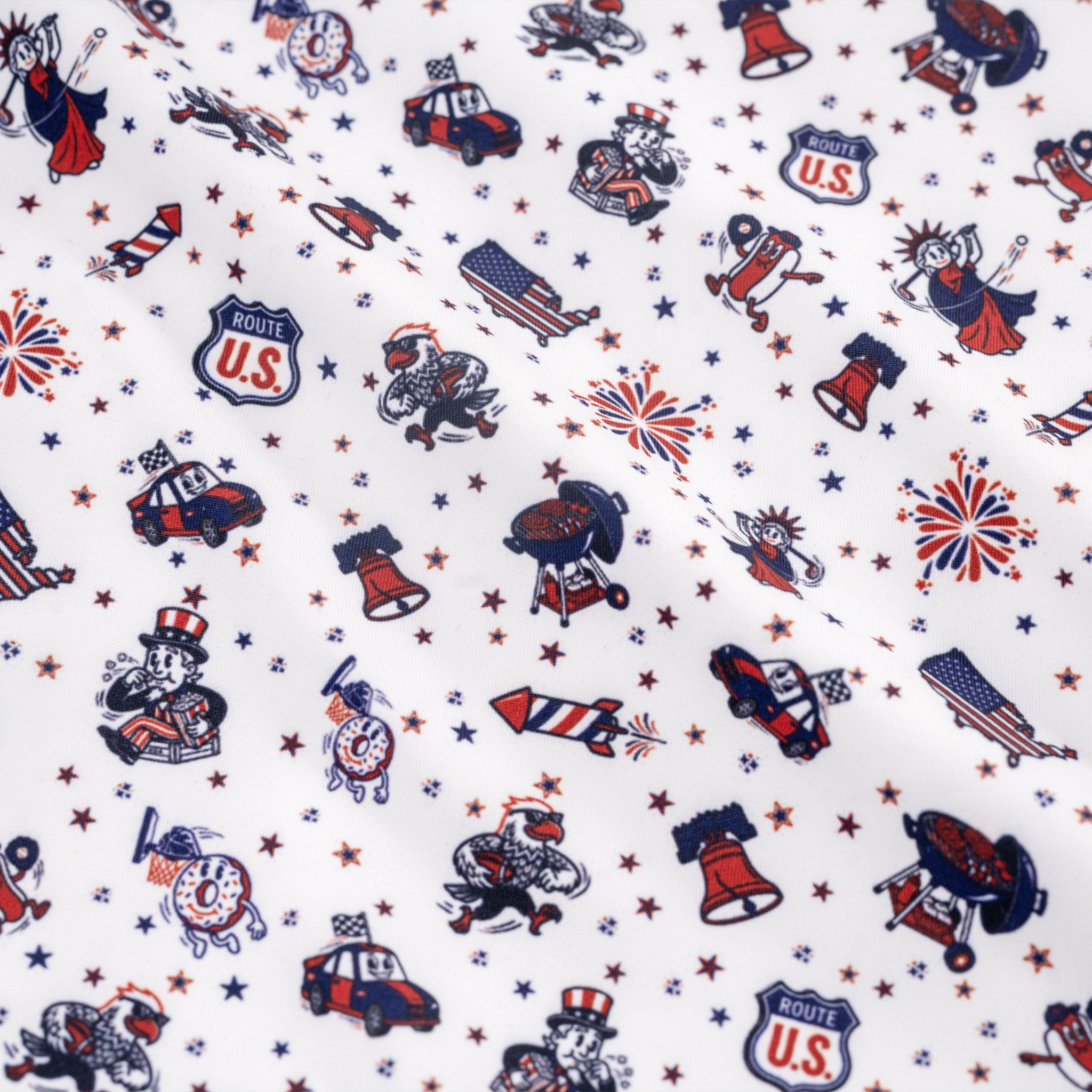 Patterned fabric with patriotic designs including cars, flags, and stars on a white background.