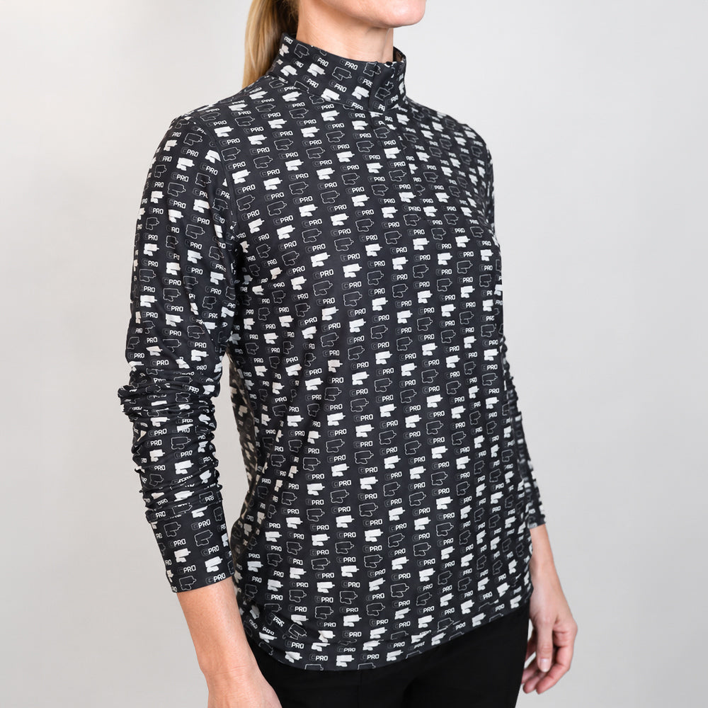 A woman wearing a black quarter-zip shirt with a white repeating geometric logo pattern, photographed against a light gray studio background.