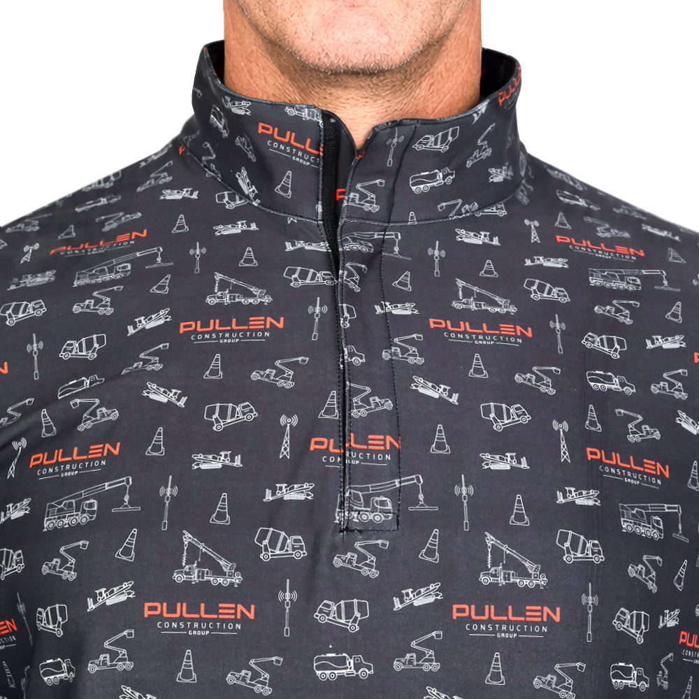 A close-up of a man wearing a dark charcoal gray quarter-zip pullover with an all-over construction-themed print featuring white line drawings of cranes, cones, and tools, and orange 'PULLEN CONSTRUCTION' logos.